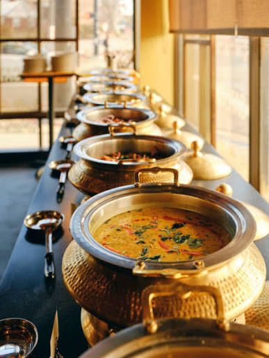 Row of traditional hammered copper handis filled with hot Punjabi dishes